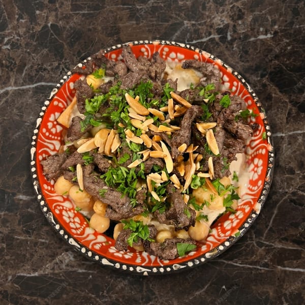 A vibrant red and white plate filled with beef shawarma, chickpeas, parsley, and sliced almonds.