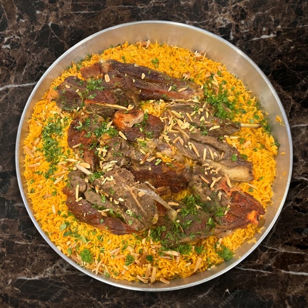 A large platter of golden rice topped with roasted lamb, garnished with parsley and slivered almonds.